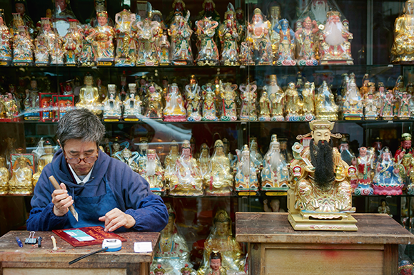 在七十年代開業的郭記木器雕刻，店內神像佛像近1,000個，以文武財神最受顧客歡迎。圖為老闆郭一天。