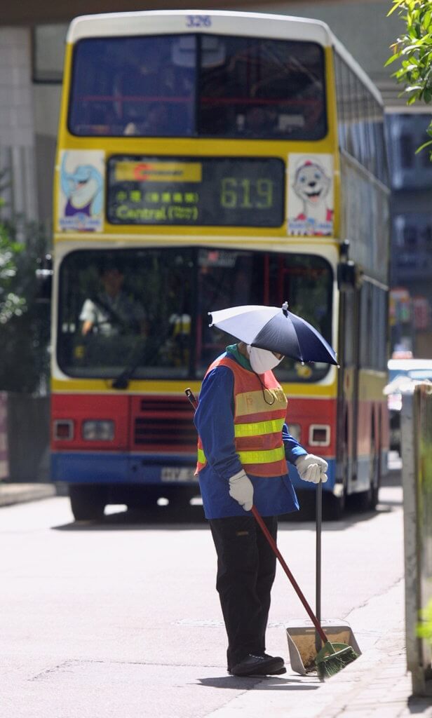 A street sweeper wears an umbrella hat to avoid the hot morning sun as she cleans the side of the road in Hong Kong, 12 July 2003. Street sweepers have been visibly out in full force since the government announced in May measures to clean up its filthy streets in a bid to eliminate the SARS virus that hit the city this past spring.    AFP PHOTO/Richard A. BROOKS (Photo by RICHARD A. BROOKS / AFP)