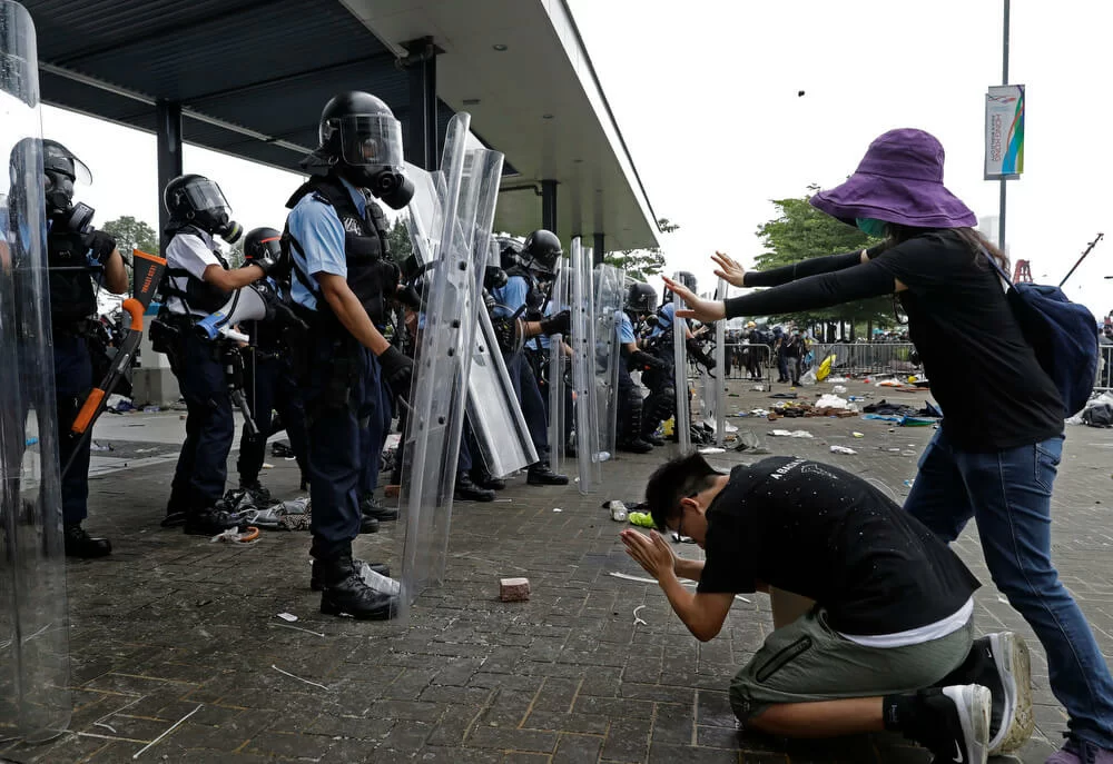 A protester bows to riot police after they fire tear gas towards protesters outside the Legislative Council in Hong Kong, Wednesday, June 12, 2019. Hong Kong police used tear gas and high-pressure water hoses against protesters who had massed outside government headquarters Wednesday in opposition to a proposed extradition bill that has become a lightning rod for concerns over greater Chinese control and erosion of civil liberties in the semiautonomous territory.(AP Photo/Vincent Yu)