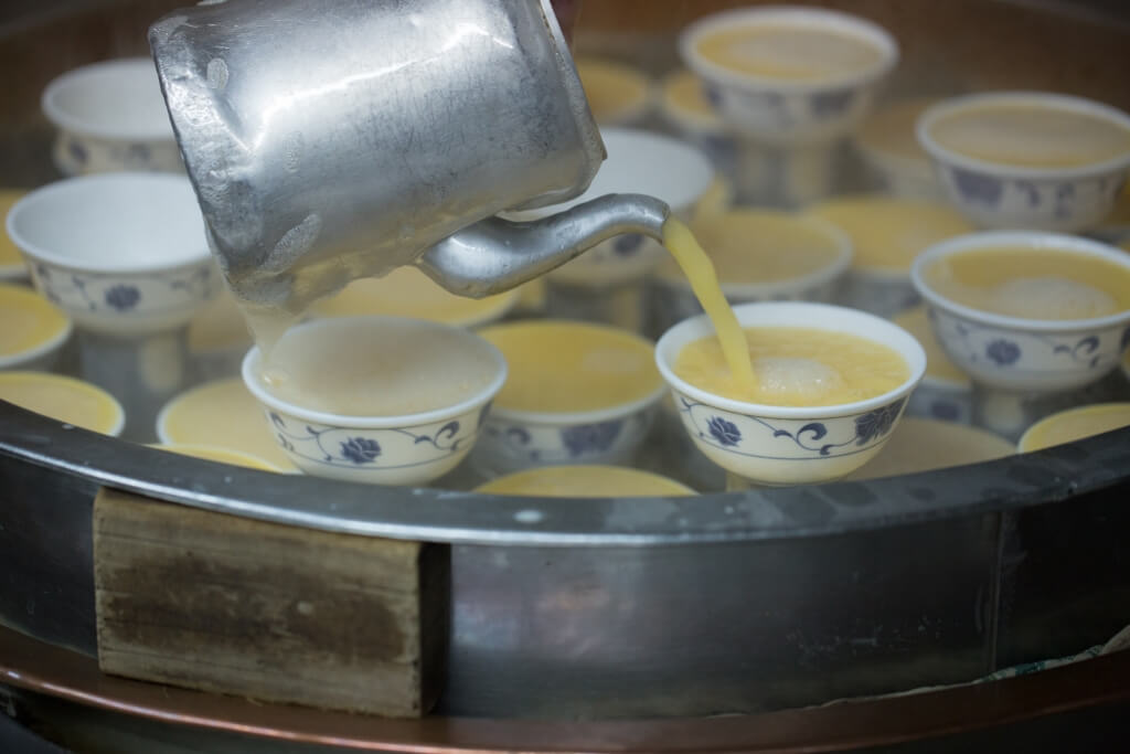 每天鮮製燉蛋，師傅把蛋漿調 好淋落碗中，再逐碗舀走泡沫， 才有如此滑溜的質感。