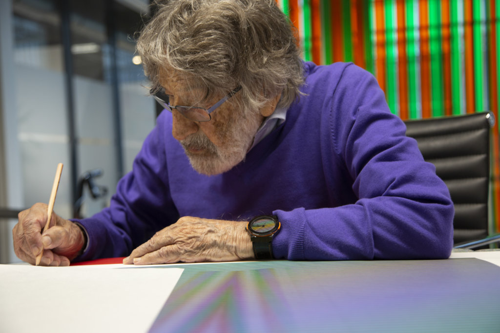 carlos-cruz-diez-signing-an-artwork-in-his-workshop-paris-france-2018-photo-atelier-cruz-diez-paris-lisa-preud-homme