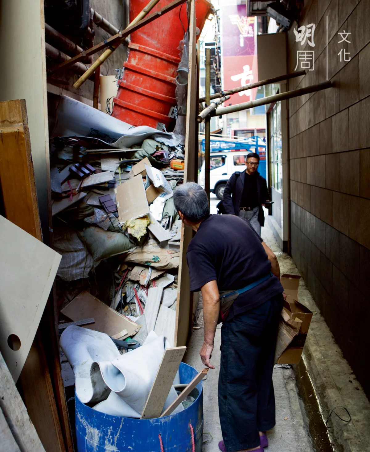 她在一堆建築廢物中拖出一小塊紙板，廢料差點傾瀉而下。