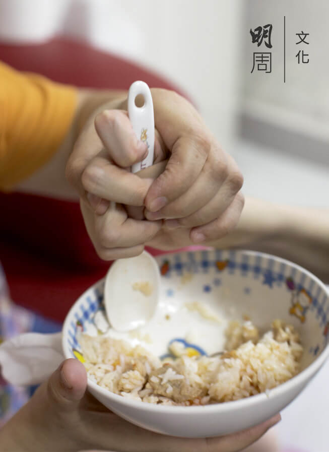 阿山手部協調欠佳，自己舀飯有困難，媽媽手把手教。