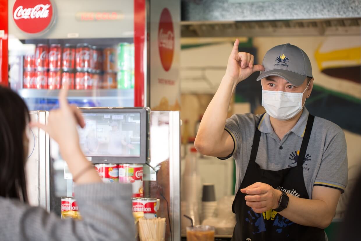 這裏有飯檔、麵檔，也有茶水檔，由聾啞人士負責，儼然一個手語教室，客人可即學即用，以手語柯打飲品，咖啡、奶茶、阿華田，加奶或走奶，一份、兩份或三份糖，比手劃腳代替嘴巴言語。