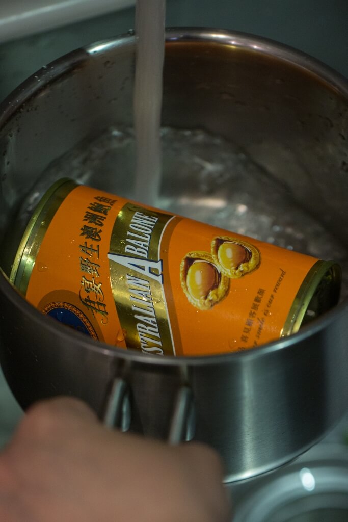 將罐頭鮑連罐放水煲煮，可令鮑魚吃來有溏心軟腍的效果。
