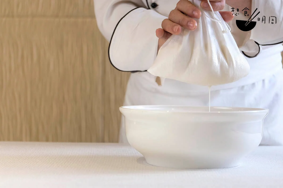 過濾杏汁。在家可以用魚湯袋做，不過在中菜廳會用孔洞幼密的麵粉袋，提升杏仁茶的滑溜感。