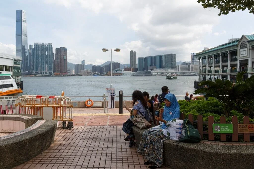 A migrant worker (R) employed as a domestic maid speaks to a loved one via a video call on her smartphone on her day off at the Central ferry piers in Hong Kong on August 13, 2017. (Photo by TENGKU Bahar / AFP)