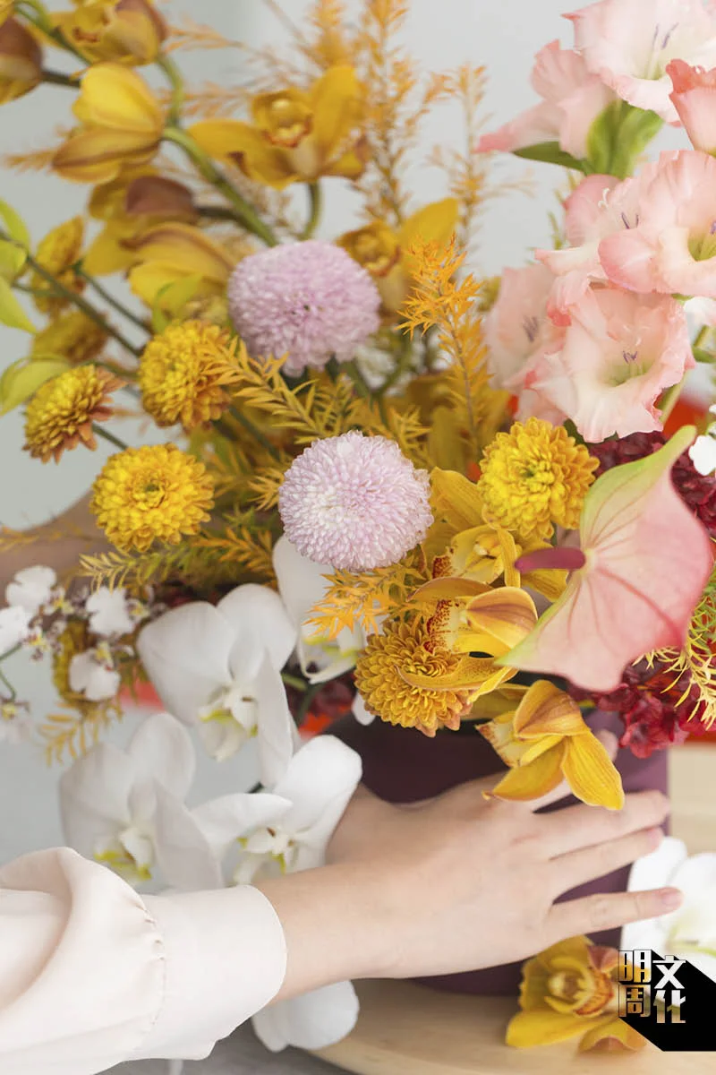 加上蝴蝶蘭和跳舞蘭，白色的花材能起點綴和中和作用，亦可加上金松。Cherie特別提醒大家，同樣的花材可放置在斜角位。