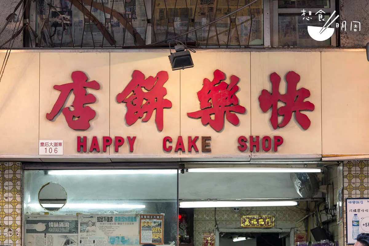 位於灣仔皇后大道東的「快樂餅店」，開業至今超過四十年。不論內外，店子都保留着上世紀七十年代的麵包店風格，包括這組「白底紅字」的招牌，簡單卻顯眼、醒目。 