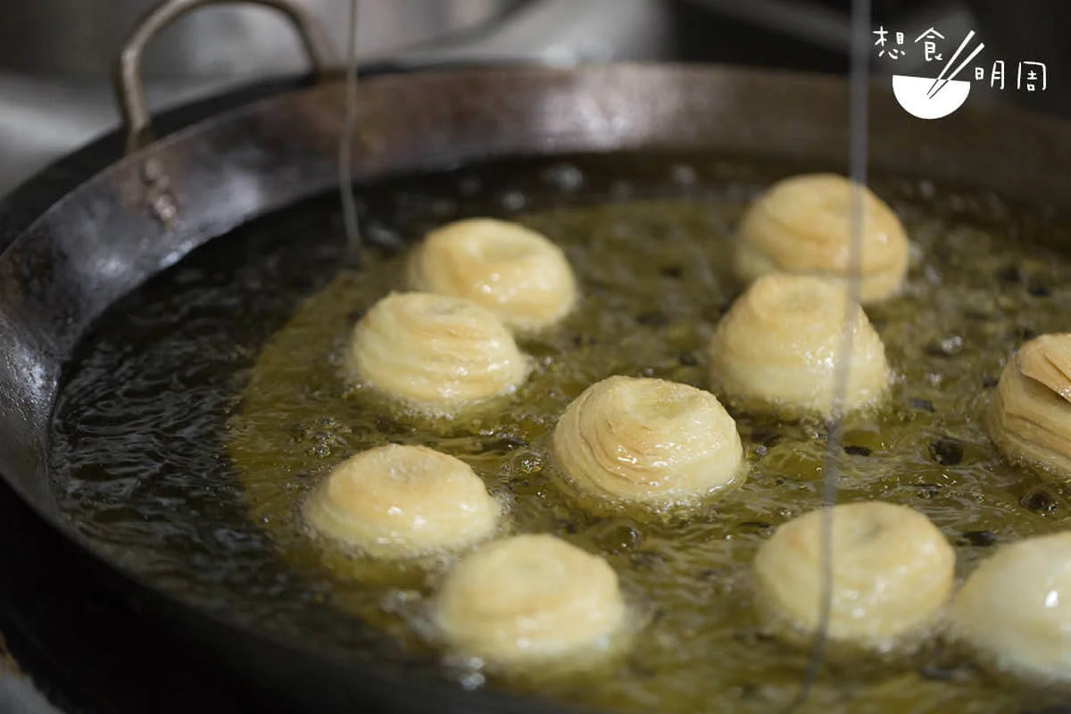 開中火，用油浸炸月餅。為求色澤金黃、平均，師傅需不時把轉動盤子。 