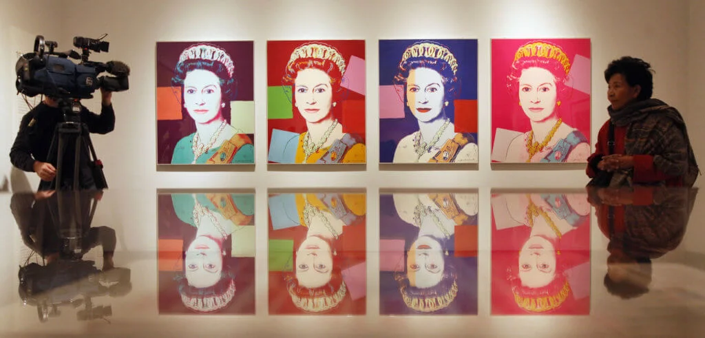 LONDON, ENGLAND - MAY 16: A woman walks past an artwork of Her Majesty Queen Elizabeth II by Andy Warhol as it's being filmed in the National Portrait Gallery's exhibition 'The Queen: Art & Image' on May 16, 2012 in London, England. The exhibition, which opens to the public on May 17, 2012 and runs until October 21, 2012, features a wide-ranging display of images of The Queen from throughout her 60 year reign. (Photo by Oli Scarff/Getty Images) (Photo by OLI SCARFF / GETTY IMAGES EUROPE / Getty Images via AFP)