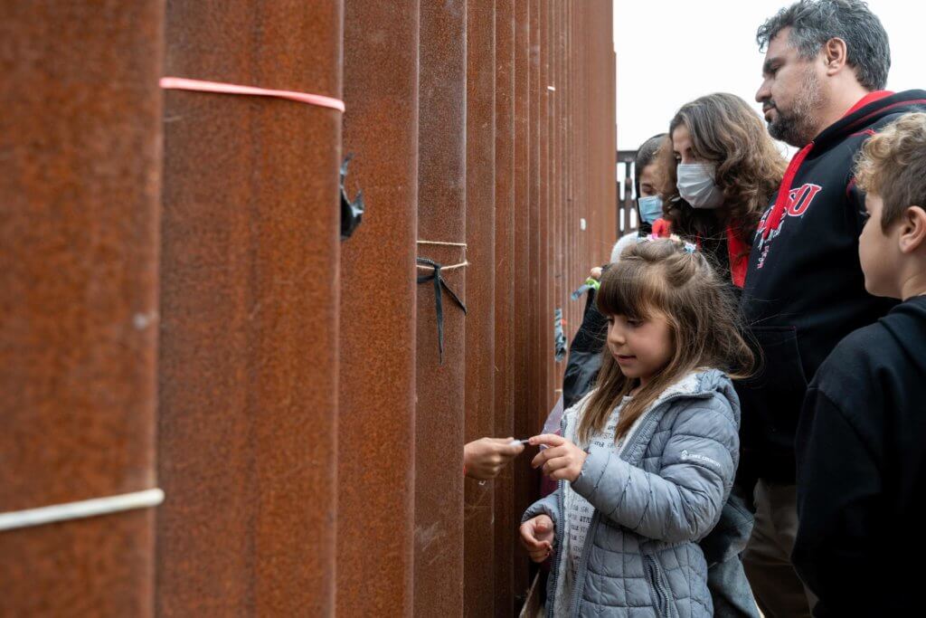 一個在牆外的女孩，將自己的手錶除下，送給牆內的孩子。這家人早前亦為滯留的移民捐贈各種物資。（攝：Joe Orellana）