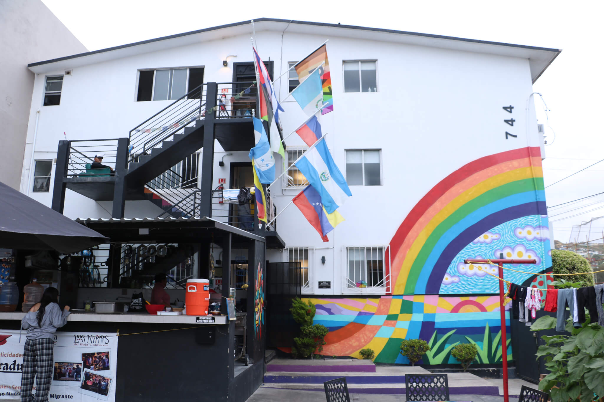 光之屋的外牆繪上彩虹壁畫，並掛滿不同國旗，象徵來自世界各地的人在這裏共同生活。