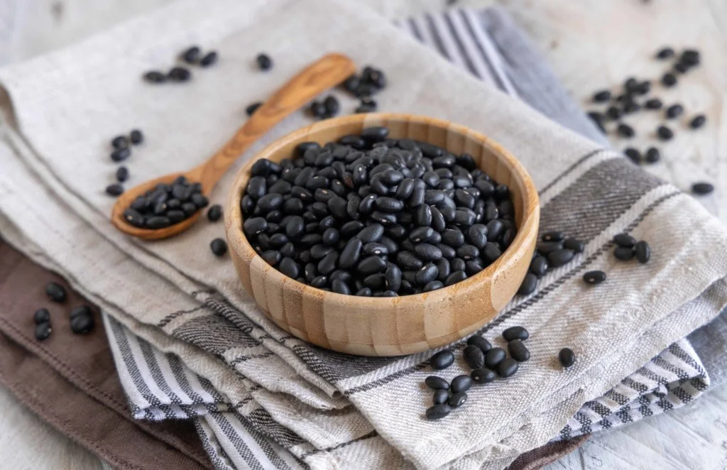 wooden-bowl-full-dried-black-beans-with-wooden-spoon-kitchen-towels-wooden-table-close-up-healthy-eating-vegetarian-concept-traditional-latin-american-cousin-ingredient