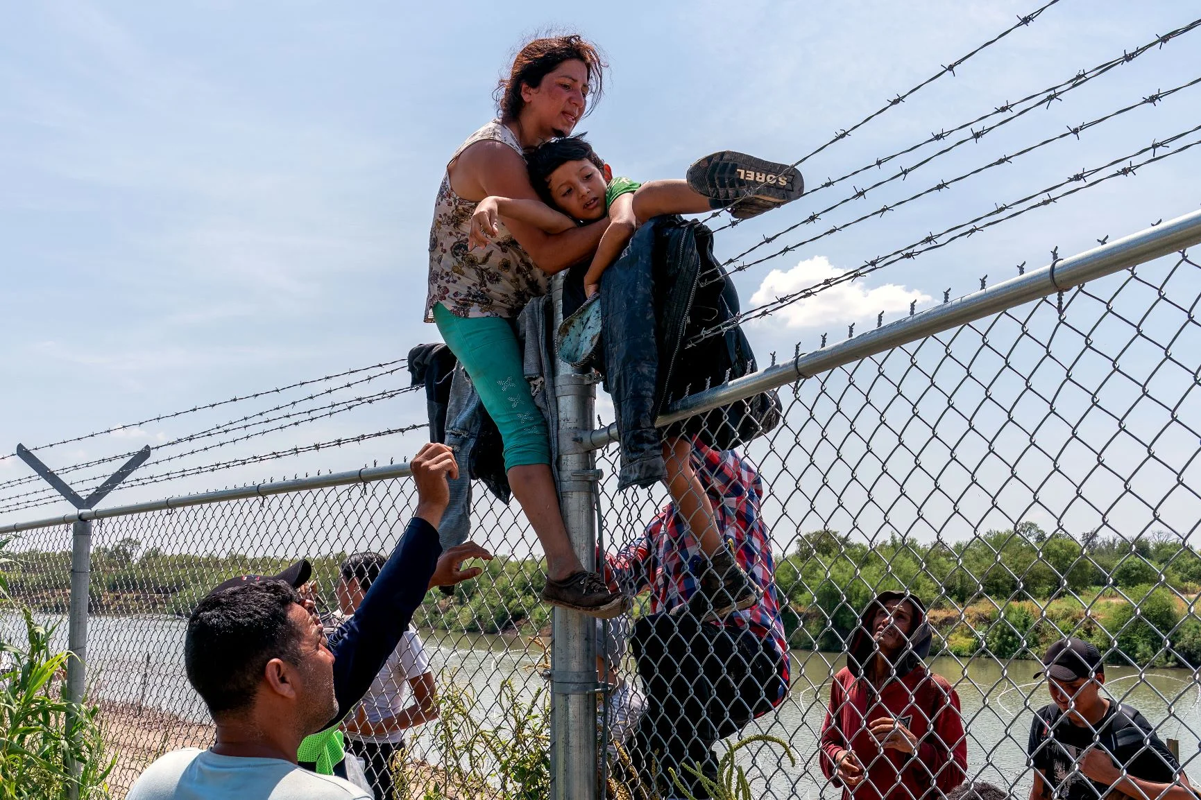 從墨西哥出發的移民者爬過鐵絲網圍欄， 越過格蘭河（Rio Grande）抵達美國。照片攝於八月。（SUZANNE CORDEIRO / AFP）