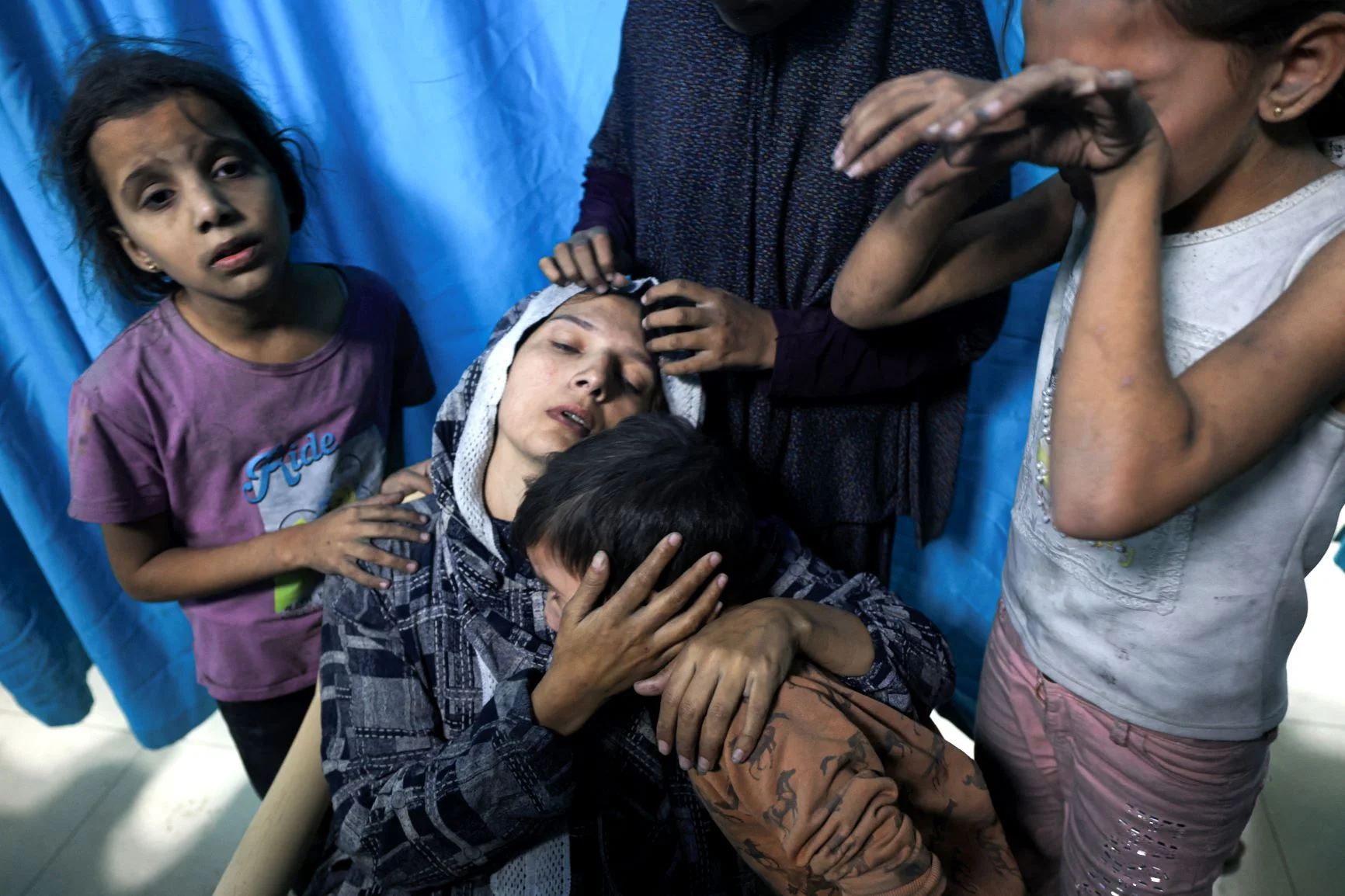 十一月，以色列空襲加沙地帶。圖中的巴勒斯坦婦女因家園被擊中受傷需求醫，抵達位於加沙南部城市汗尤尼斯（Khan Yunis）的 納賽爾醫院（Nasser hospital），她的子女陪伴在側。（MAHMUD HAMS / AFP）