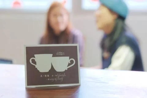 「Coffee with Strangers」明信片上兩杯有耳咖啡的圖案，「耳」代表聆聽，設計極富心思。