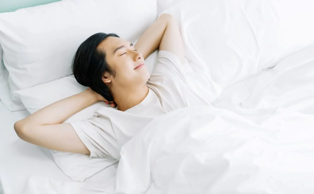 top-view-young-asian-man-smiling-while-sleeping-his-bed-relaxing-morning-rest-relax-good-mood-lifestyle-concept
