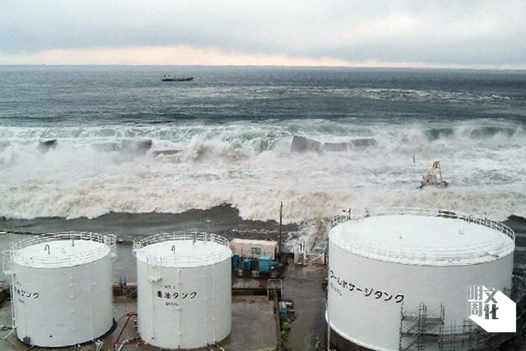 照片由東京電力公司於二〇一一年三月十一日拍攝，海嘯翻越海堤，洶湧的海水正湧去福島第一核電廠。（法新社）