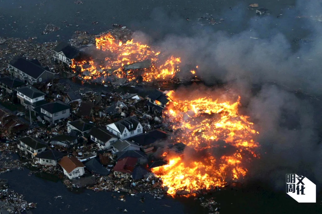 三一一大地震中，日本北部宮城縣名取市的房屋遭到海嘯襲擊後發生大火。（法新社）