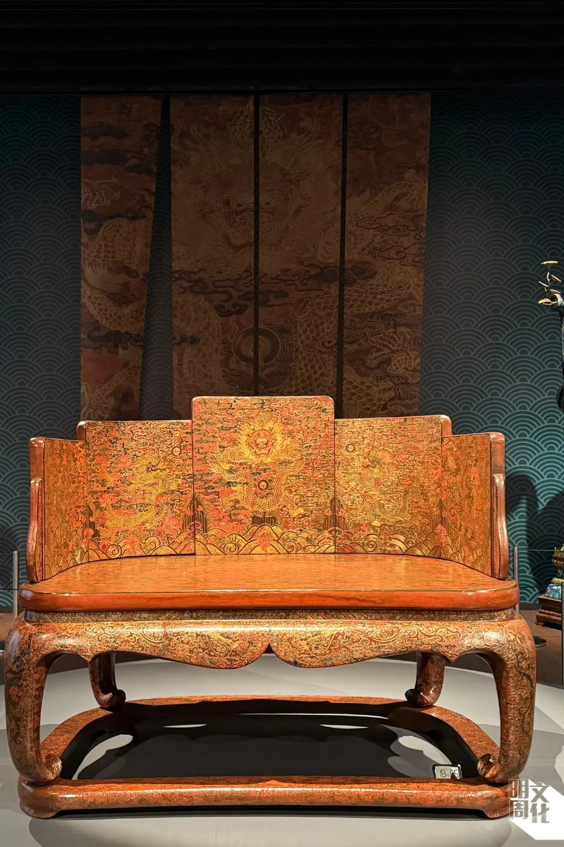 誕生於清代康熙晚年（1662-1722） ，為清朝康熙皇帝的御製寶座，是傳世寶座當中唯一結合戧金及填漆兩種髹飾工藝的珍品。椅背由五屏組成，寶座方中帶圓，四角呈弧形，座圍以雕填手法飾有海水江崖紋、雲紋和龍紋，座面雕填開光、點綴拐子紋及各式折枝花卉等，手工極其精細。