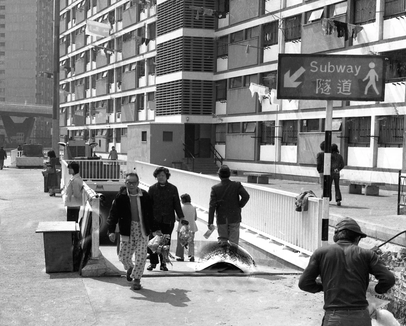 彩虹邨居民穿行於隧道中，隧道入口彎曲是由於底片破損所致。攝於一九七五年。（圖片由高 添強提供）