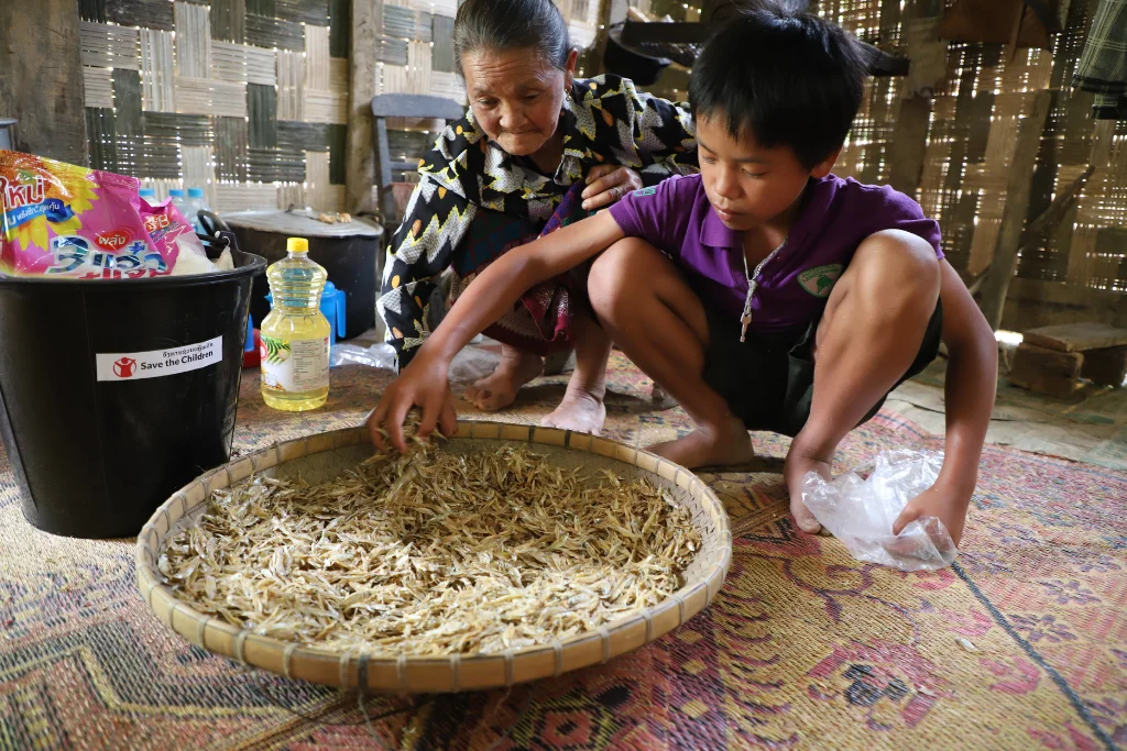 Chan與祖母Phon獲發食物、物資包及現金等援助 (Phavanh Sosamphan/Save the Children Laos)