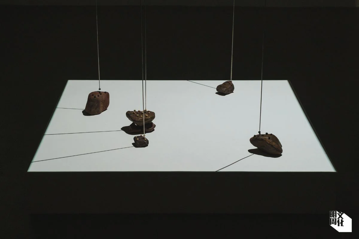 蘇詠寶《製模》，2025，裝置尺寸可變。 材料：赤礦鐵、紅豆、黃豆、黑豆、磁石、金屬棒、摩打。意念：磁性豆粒懸於赤礦鐵上方，在磁場中相斥，形成獨特運動軌跡。展現自然力量與物件的關係既神秘無形，卻又易於察覺。