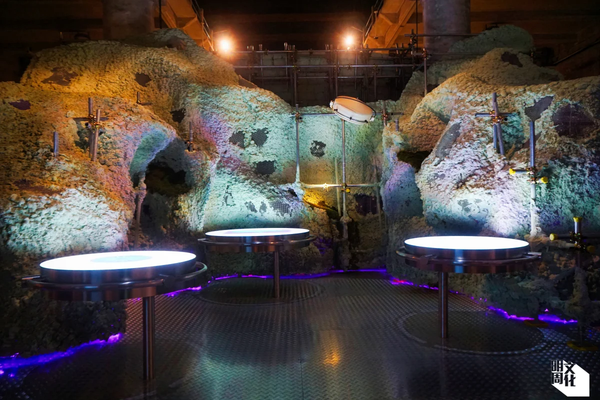 穿過高溫房，眼前巨大的展品是「The Other Side of the Hill」。山體兩面，一面是巨大磚牆，呈現人類真相，全球人口預計在數十年後升至一百億，隨後以相近速度下降，甚至有機會回落至工業化前水平；山的另一面則是蓬勃微生物，象徵人類或可依仗自然智慧來面對未知，例如從微生物的強大適應力中學習。