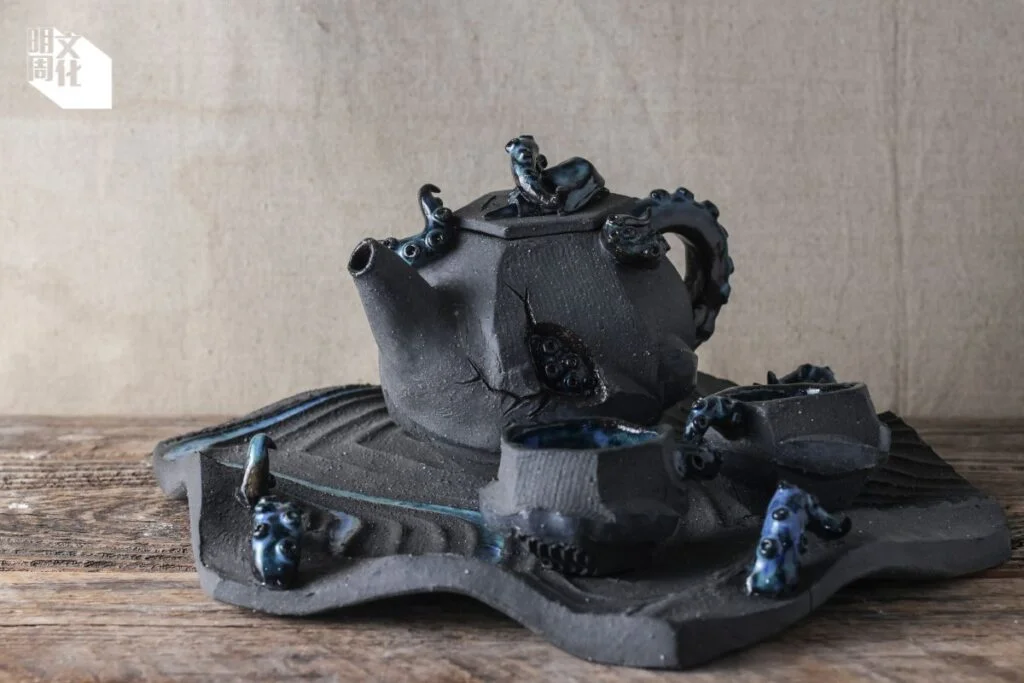 邱志崇《小藍蟹歷險記》：作品使用花崗岩細目黑土，茶壺表面刻意不上釉，保留陶泥本身的深灰色。徐瑛娟說希望使用者感受到石頭質地。