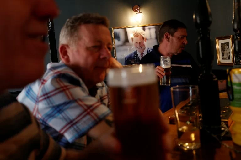 A portrait of Britain's Prince Harry hangs on the wall as drinkers at a bar inside a pub called 'The Prince Harry' near Windsor Castle in Windsor, west of London on May 15, 2018, as preparations get underway for the forthcoming Royal wedding. Britain's Prince Harry and US actress Meghan Markle will marry on May 19 at St George's Chapel in Windsor Castle. / AFP PHOTO / Adrian DENNIS