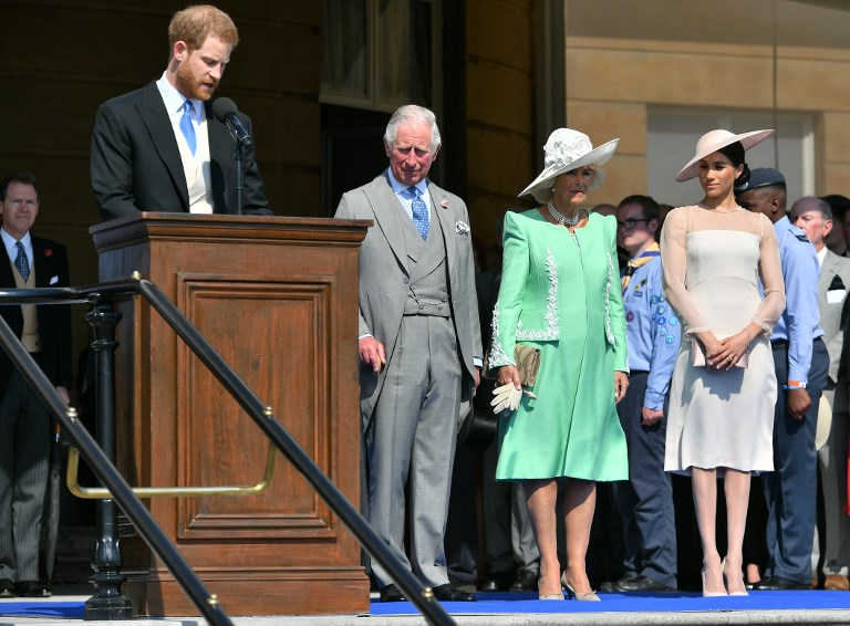 Britain's Prince Charles, Prince of Wales (2L), his wife Britain's Camilla, Duchess of Cornwall (C), and Britain's Meghan, Duchess of Sussex (Centre R), listen as her husband Britain's Prince Harry, Duke of Sussex (L), speaks during the Prince of Wales's 70th Birthday Garden Party at Buckingham Palace in London on May 22, 2018. The Prince of Wales and The Duchess of Cornwall hosted a Garden Party to celebrate the work of The Prince's Charities in the year of Prince Charles's 70th Birthday. / AFP PHOTO / POOL / Dominic Lipinski
