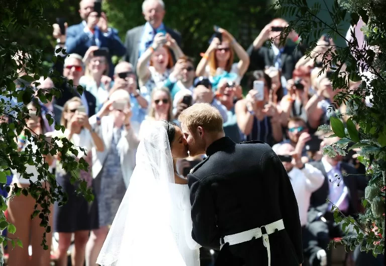 Britain's Prince Harry, Duke of Sussex kisses his wife Meghan, Duchess of Sussex as they leave from the West Door of St George's Chapel, Windsor Castle, in Windsor, on May 19, 2018 after their wedding ceremony. / AFP PHOTO / POOL / Danny Lawson