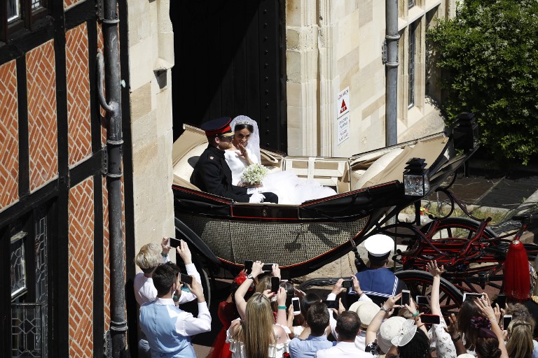 Britain's Prince Harry, Duke of Sussex (L) and his wife Meghan, Duchess of Sussex (R) begin their carriage procession in the Ascot Landau Carriage after their wedding ceremony at St George's Chapel, Windsor Castle, in Windsor, on May 19, 2018. / AFP PHOTO / POOL AND AFP PHOTO / Odd ANDERSEN