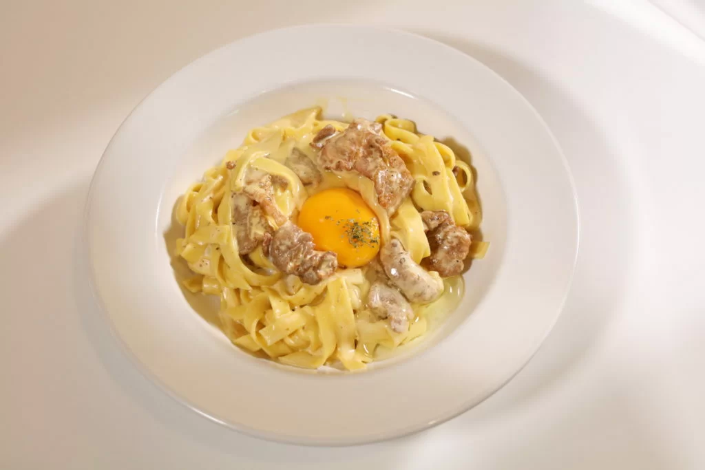 闊條麵以忌廉汁配自家醃肉來炒，加上日本生蛋，口感香濃。 