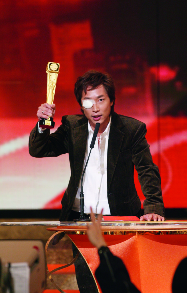 憑《鐵血保鏢》奪得男角色獎,眼睛貼着紗布上台領獎。