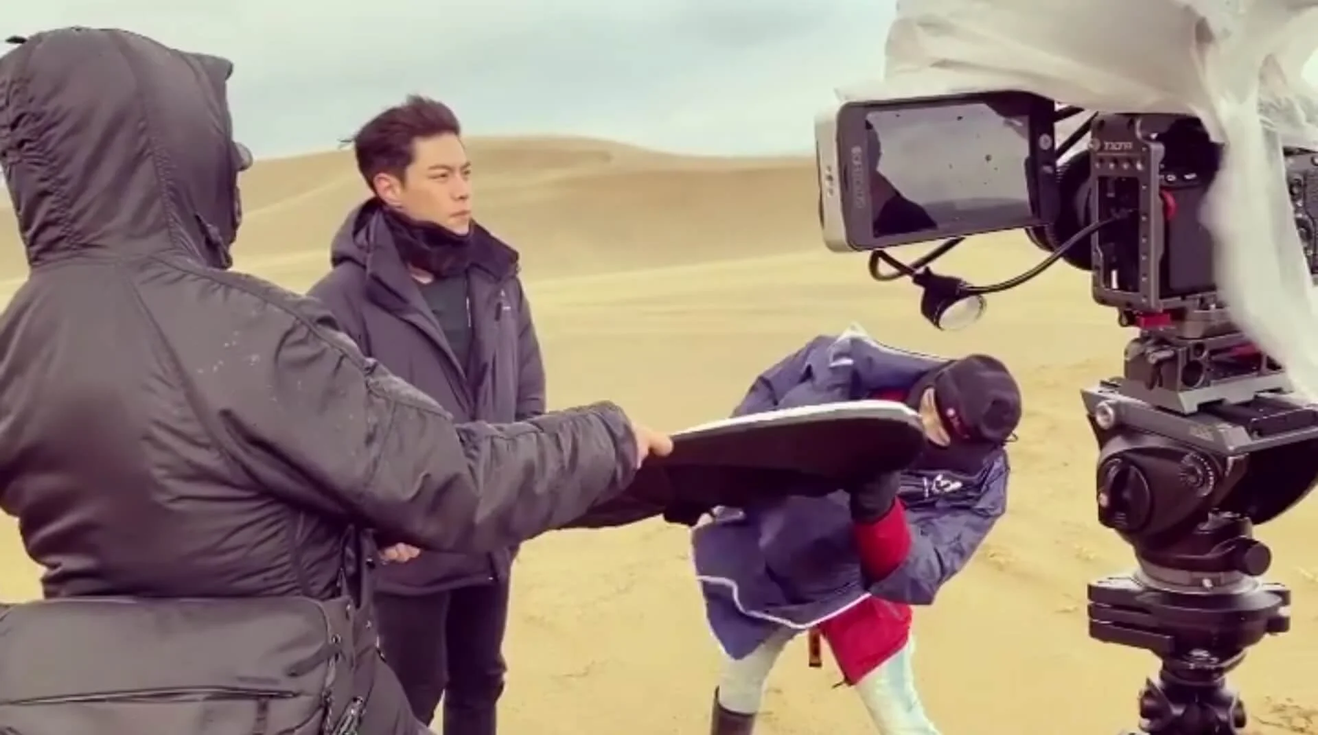 因鳥取砂丘面向日本海，經常刮起大風，只見兩位攞住反光板的工作人員，被吹到搖擺不定，非常吃力才能站穩。