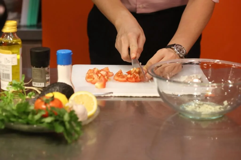 放入1/4個檸檬汁、1湯匙橄欖油、適量鹽及蒜蓉，並將番茄切粒。