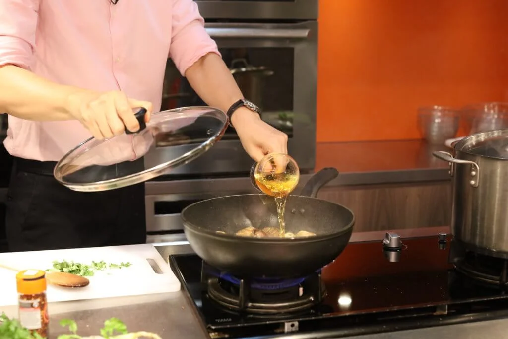 平底鍋內加入少許橄欖油、蒜蓉、辣椒粉、已吐沙的蜆、白酒，蓋上鍋蓋。