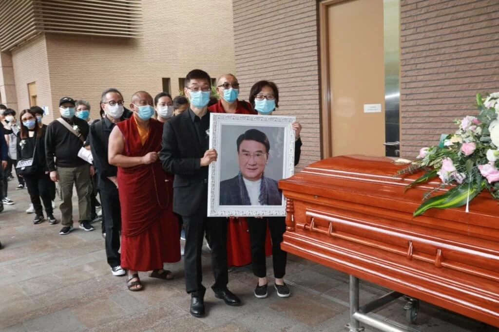 兒子譚廣銘及女兒瑩瑩手持父親遺照，跟親友送別炳哥最後一程。