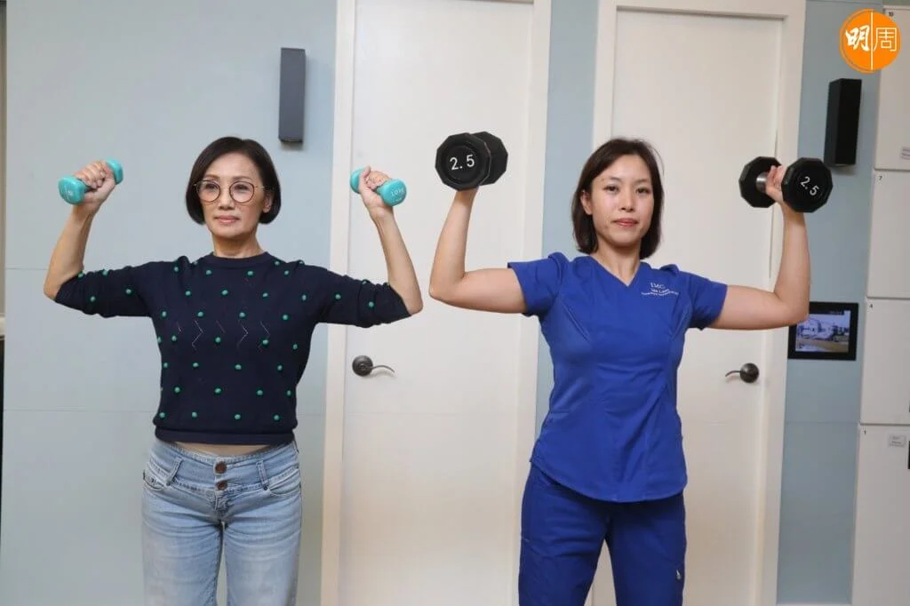 雙手持水樽或其他物件，雙臂舉高緊胋耳邊，