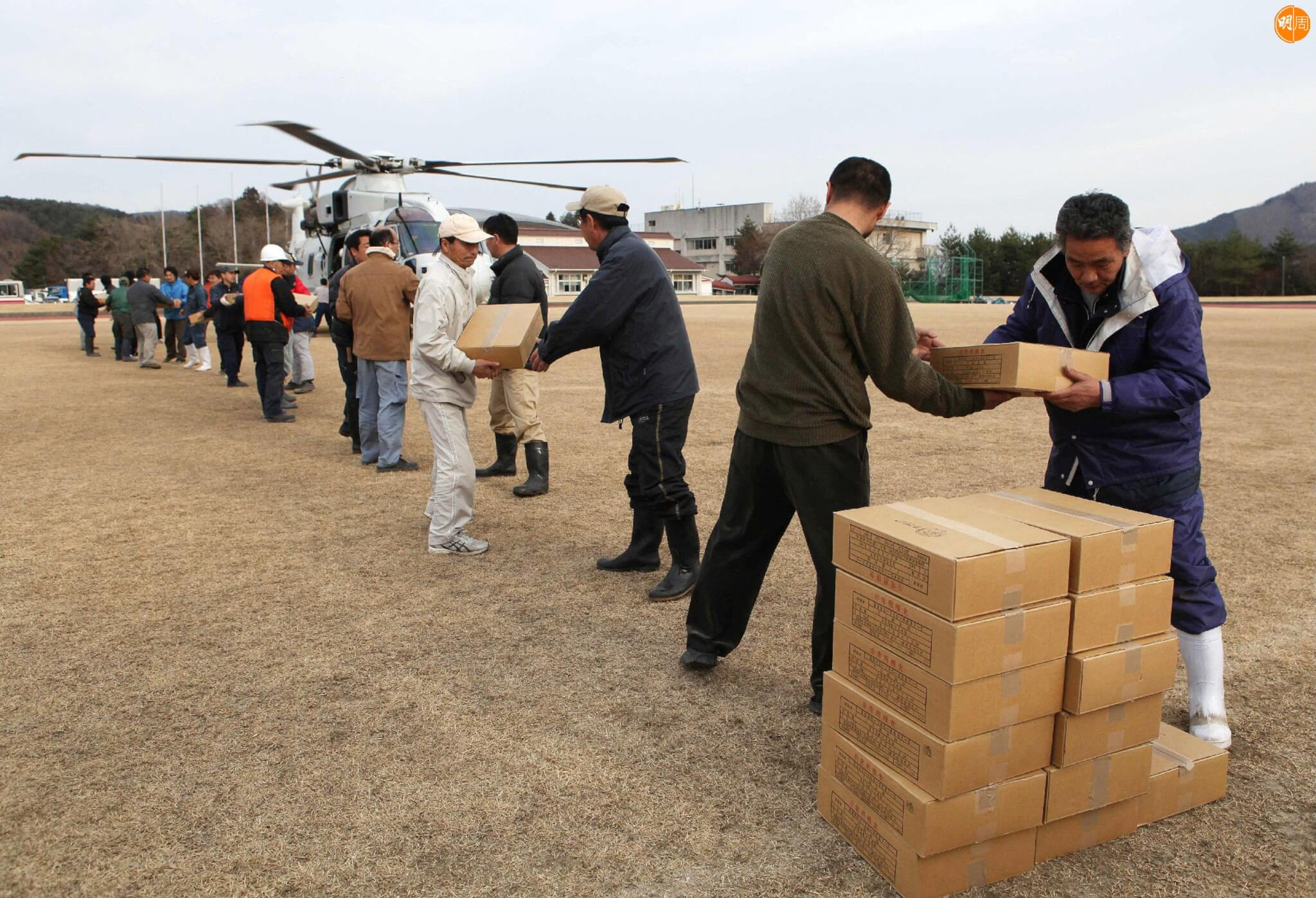 Local residents and town staff carry out relief supplies effects from a helicopter in the town of Onagawa in Miyagi prefecture on March 14, 2011 three days after a massive 8.9 magnitude earthquake and tsunami devastated the coast of eastern Japan. A new explosion at a nuclear plant in nearby Fukushima prefecture hit punch-drunk Japan on March 14 as it raced to avert a reactor meltdown after a quake-tsunami disaster that is feared to have killed more than 10,000 people. AFP PHOTO / JIJI PRESS (Photo by JIJI PRESS / JIJI PRESS / AFP) / Japan OUT