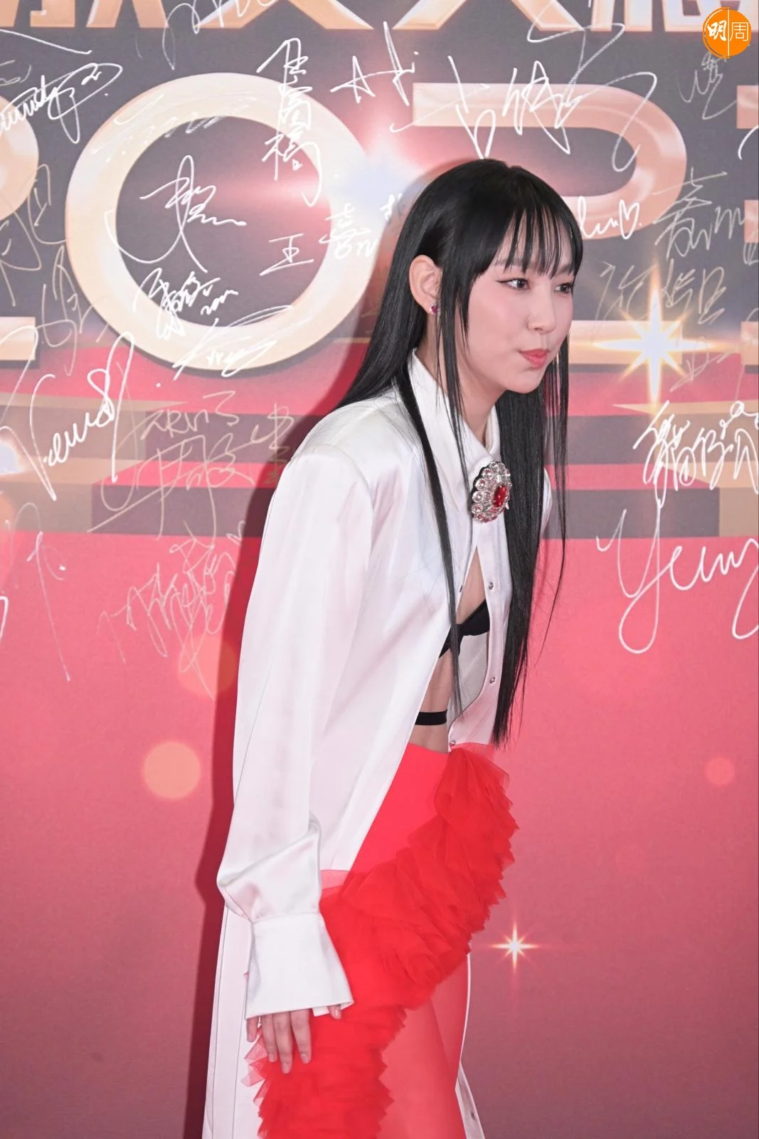 Gigi一身性感打扮，以白色長褸配黑Bra，下身襯鮮紅喱士短裙配同色絲襪，造型大膽。